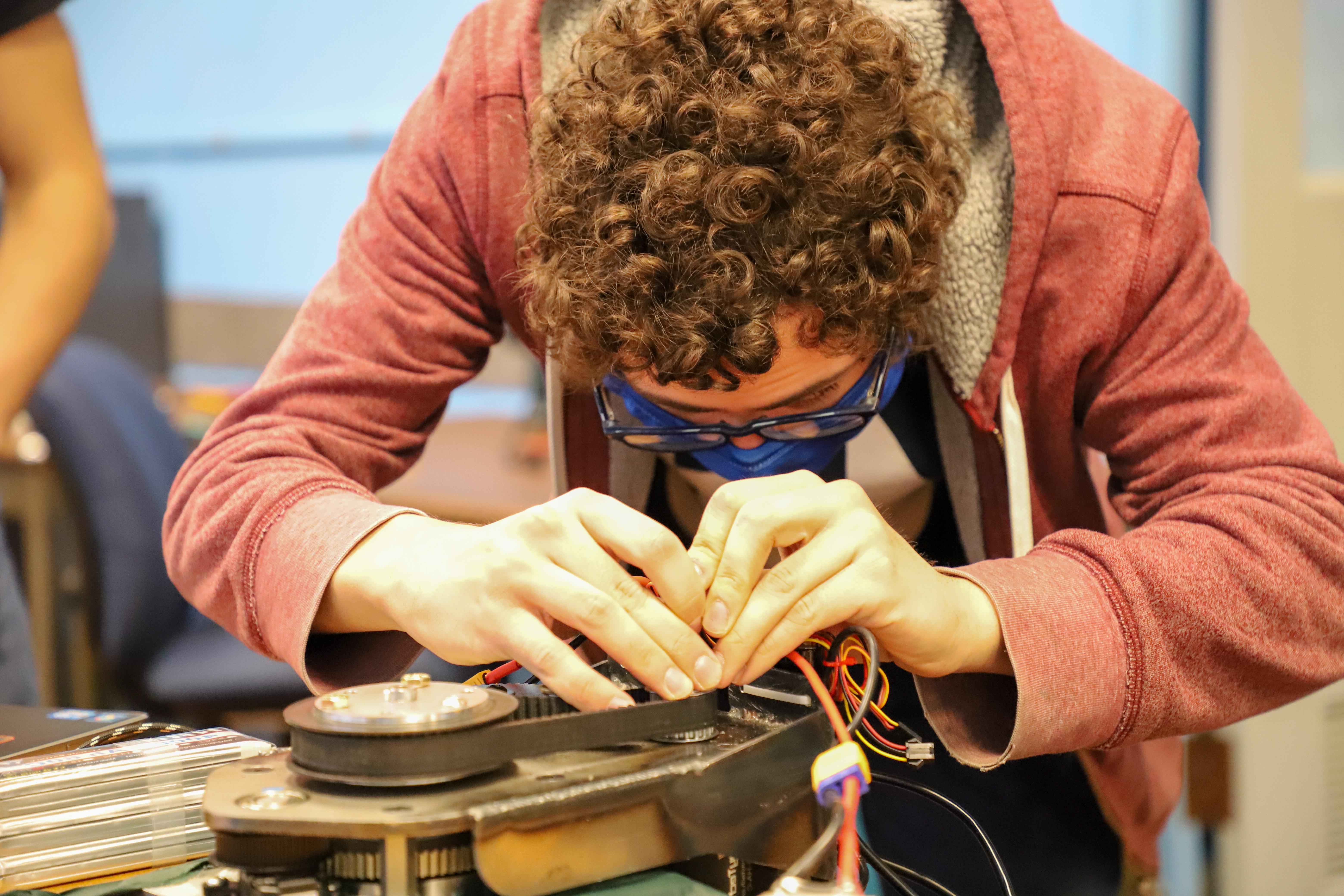 A 正规的赌博app student works on the wiring of the robot's wheel.